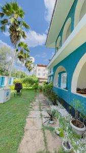 a blue building with palm trees in a yard at Gallivanters Hostel in Dar es Salaam