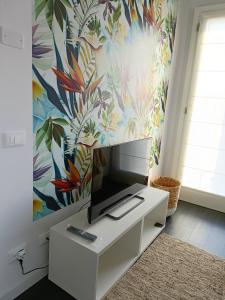 a tv on a white cabinet in a room with a floral wallpaper at Boutique apartment Alla Dolce Vita in Vicenza