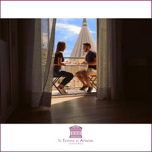 un uomo e una donna seduti a un tavolo sul balcone di Il Tempio di Athena - Cultura e Relax a Siracusa a Siracusa