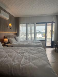 a hotel room with two beds and a large window at Hotel Stella in Kusadası