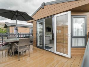 a patio with a table and an umbrella on a deck at Carolina Lodge in Evesham