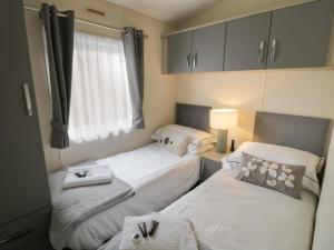 two beds in a small room with a window at Carolina Lodge in Evesham