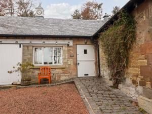 a small brick house with a white door and a clock at Harness Lodge in Seahouses