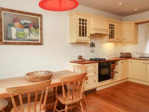 a kitchen with a wooden table and some chairs at Harness Lodge in Seahouses