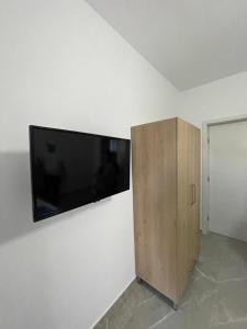 a flat screen tv on a white wall with a wooden cabinet at Villa Soni Oruci in Ksamil