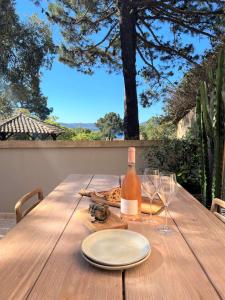 a wooden table with a bottle of wine and glasses at Casetta Cala Rossa in Lecci