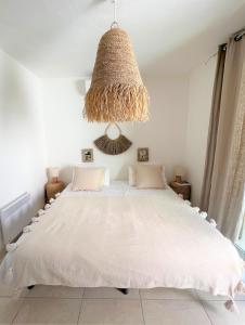 a bedroom with a large white bed with a chandelier at Casetta Cala Rossa in Lecci