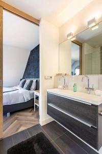 uma casa de banho com um lavatório, um espelho e uma cama em Rue Haute by M&M 4 sterren bed en breakfast vlakbij Maastricht em Eben-Emael