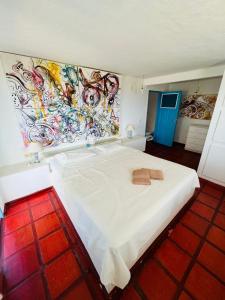 ein Schlafzimmer mit einem weißen Bett und einem Gemälde an der Wand in der Unterkunft MYKONOS HOUSE in Aquiraz