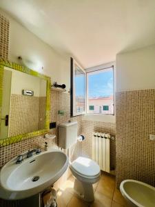 uma casa de banho com um lavatório, um WC e uma janela. em A casa di Mario e Nenè em Viareggio