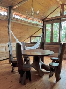 a wooden table and chairs in a room with a hammock at Eco Lodge in Alto Paraíso de Goiás