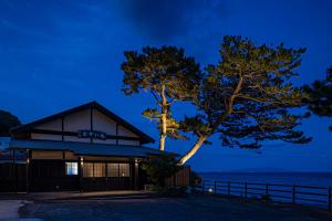 a building with a tree in front of the ocean at La-gom in Inatori