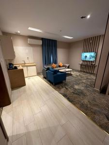 Banan Hotel Suites في تبوك: غرفة معيشة مع أريكة زرقاء ومطبخ