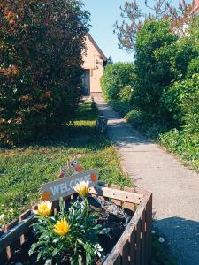 a sign in a garden with flowers on a sidewalk at LakeLove Házikó Sopron- Erdő és tópart mellett in Sopron