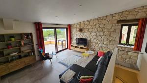 Casa dell’ Orso في Abbateggio: غرفة معيشة مع أريكة وجدار حجري