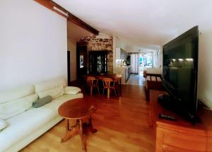 Una sala de estar con un sofá blanco y un televisor de pantalla plana. en Les Chambres du Clos des Capucins, en Barjac