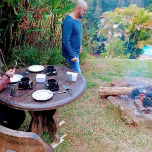 a man standing next to a table next to a fire at Chalé Serra Cantareira in Mairiporã