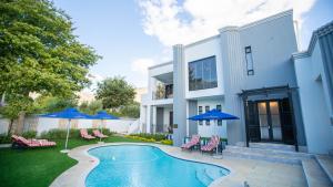 a house with a swimming pool with chairs and umbrellas at Kilima Franschhoek in Franschhoek