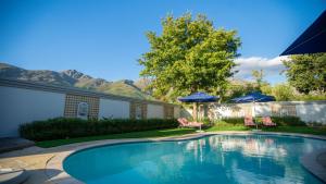 - une piscine avec des chaises et des parasols dans la cour dans l'établissement Kilima Franschhoek, à Franschhoek