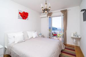 a white bedroom with a bed and a large window at Guesthouse Slavka in Dubrovnik