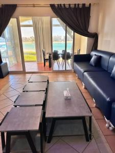 a living room with a blue couch and tables at درة العروس - القرية الحالمة - شقة دور أرضي على البحر - Dream Village in Durat Alarous