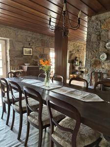 a large wooden table with chairs and a vase of flowers at Casa dos três rapazes in Monte Córdova
