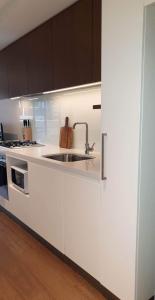 a white kitchen with a sink and a stove at Urban Eden in South Yarra in Melbourne