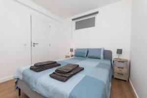 セジンブラにあるCasa das Andorinhas - T2 renovado com terraçoのベッドルーム1室(ブルーベッド1台、タオル付)