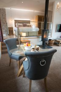 een woonkamer met een glazen tafel en een open haard bij Hawkshead Suites in Hawkshead