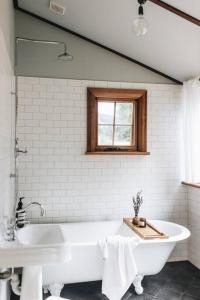a white bath tub in a bathroom with a window at Pickers Hut in Basket Range