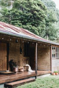 una casa de madera con un porche con plantas. en Pickers Hut en Basket Range