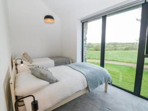 two beds in a bedroom with a large window at Pen-Y-Bryn in Llanfairpwllgwyngyll