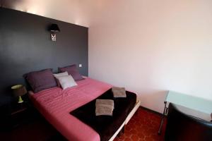 una camera da letto con letto e lenzuola e cuscini rosa di Les chambres d'hôtes de L'Oliveraie a Opio