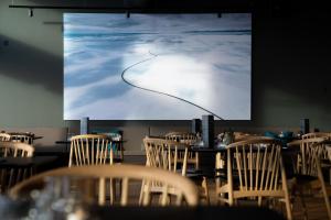 a room with tables and chairs in front of a screen at Hotel Isafjördur - Torg in Ísafjörður