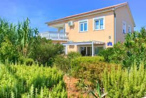 a house with a lot of plants in front of it at Holiday house NIKA with pool and jacuzzi in Linardići