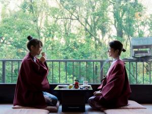 LiVEMAX RESORT Shizuoka Amagiyugashima في إيزو: كانتا جالستين على الأرض أمام النافذة