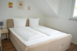 1 cama con sábanas blancas y almohadas en una habitación en Exklusive Neubauwohnung mit wundervoller Aussicht nähe Europapark und Rulantica, en Burgheim