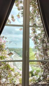 une fenêtre avec vue sur un arbre à fleurs dans l'établissement Maison Séraphine - Guest house - Bed and Breakfast, à Laon