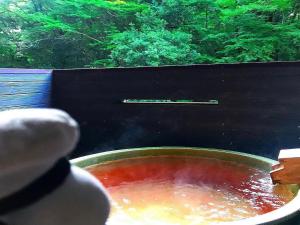 a large bowl of red soup with a persons hand in it at LiVEMAX RESORT Shizuoka Amagiyugashima in Izu