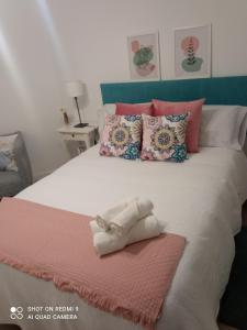 ein Bett mit einer rosa und weißen Decke und Kissen in der Unterkunft Apto Cortegada in Vilagarcia de Arousa