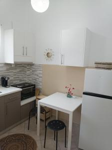 eine Küche mit weißen Schränken sowie einem weißen Tisch und Stühlen in der Unterkunft Meltemi apartments in Agia Marina