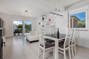 a white dining room with a table and chairs at Pool Apartment Maurina Opatija with sea view in Ičići