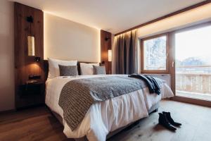 a bedroom with a large bed and a large window at Hotel Habicher Hof 4-Sterne-Superior in Oetz