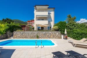 a villa with a swimming pool in front of a building at Pool Apartment Maurina Opatija with sea view in Ičići