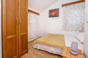 um pequeno quarto com uma cama e um armário de madeira em Apartments Zdravko em Rogoznica