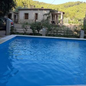 a blue swimming pool in front of a house at Casas rurales amable- yeste in Cortijo Prados