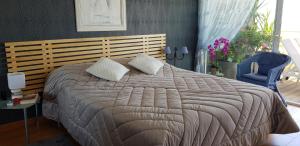 a bedroom with a large bed and a blue chair at LE PATIO in Canet-en-Roussillon