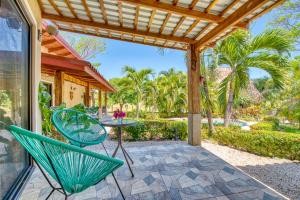 un patio con sillas, una mesa y una pérgola en Hotel Villas Tangerine en Sámara