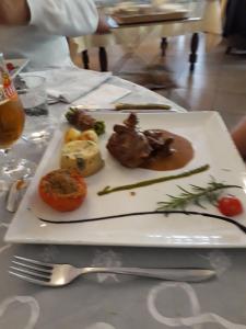 een witte plaat met vlees en groenten op een tafel bij Vue du Pont in Entraygues-sur-Truyère