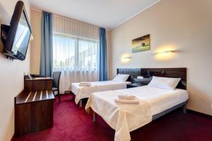 a hotel room with two beds and a flat screen tv at Focus Hotel Gdańsk in Gdańsk